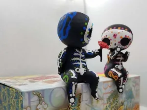 Detailaufnahme von Sugar-Skull-Paarfiguren, die auf einer dekorativen Blumendose sitzen