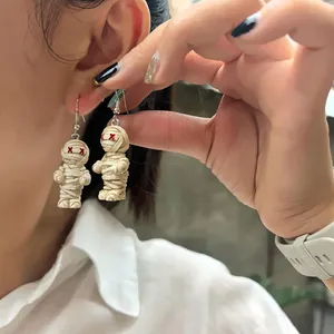 Détail de boucles d'oreilles momie d'Halloween tressées avec yeux en X portées par modèle