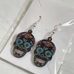 Detailed close-up view of colorful Halloween sugar skull earrings on white card packaging