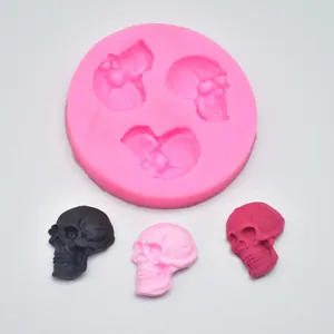 Pink silicone mold featuring three skull cavities with finished fondant samples on white
