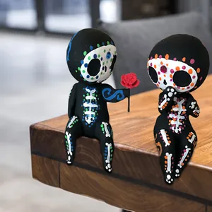 Handbemalte Skelettfiguren aus Kunstharz, die auf einem Holztisch sitzen.