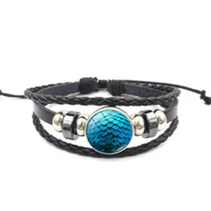 Détail d'un bracelet en cuir tressé multicouche avec une gemme à motif d'écailles bleues.