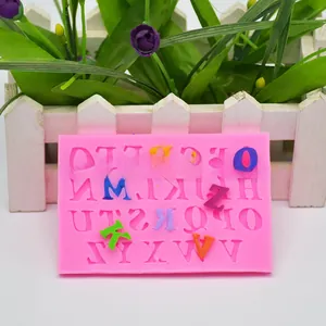 Close-up van een roze siliconen mal voor het alfabet met gekleurde letters van fondant