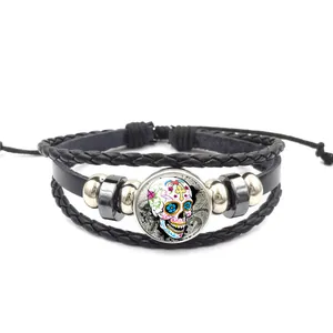 Détail d'un bracelet multicouche en cuir tressé avec un crâne de sucre mexicain coloré.