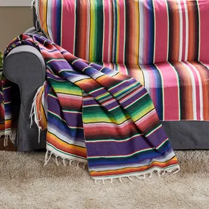Mexican serape blanket with colorful stripes and white tassels draped elegantly on a sofa