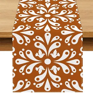 Close-up detail of Bohemian orange linen table runner with white bird and floral patterns