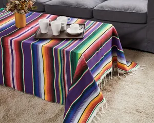 Detailed view of a Mexican Serape tablecloth with colorful stripes and white fringe.