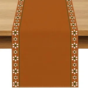 Close-up of Bohemian linen table runner with rust orange center and floral edges.
