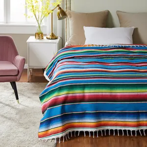 Vibrant colorful Mexican serape blanket with decorative fringe detail on a cozy bed