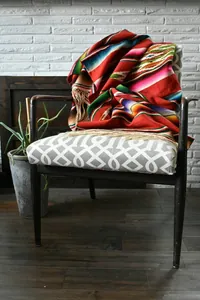 Detailed view of colorful Mexican serape fabric with fringe draped over a chair.