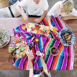 Vibrant Mexican stripe table runner with white fringes displayed at a festive outdoor party.