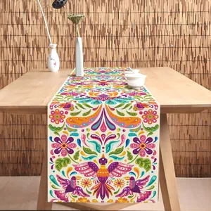 Détail d'un chemin de table mexicain avec des motifs floraux et d'oiseaux vibrants.