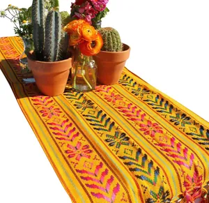 Détail montrant les motifs tissés vibrants et les glands décoratifs de ce chemin de table