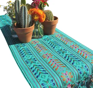 Détail d'un chemin de table mexicain avec motifs tissés turquoise et pompons colorés