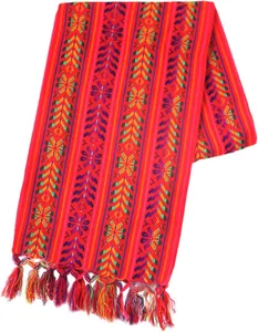 Détail du chemin de table mexicain montrant des motifs tissés et pompons colorés