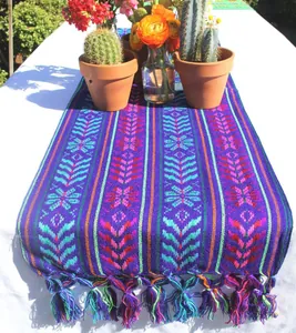 Chemin de table mexicain coloré avec motifs traditionnels et pompons sur table blanche