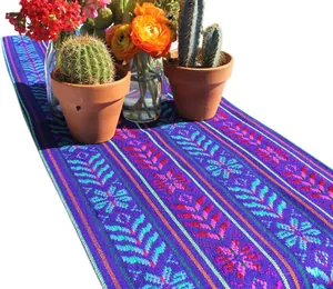 Gros plan d'un chemin de table mexicain tissé aux motifs floraux et décor de cactus.