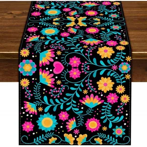 Macro view of vibrant folk floral patterns on a black festive table runner over wood texture