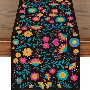 Close-up detail of colorful Mexican floral pattern on premium black linen table runner cloth