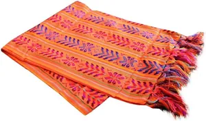 Détail d'un chemin de table mexicain coloré avec motifs tissés orange vif et pompons élégants