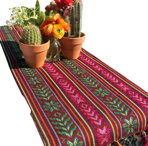 Détail d'un chemin de table mexicain coloré avec motifs géométriques tissés et franges.