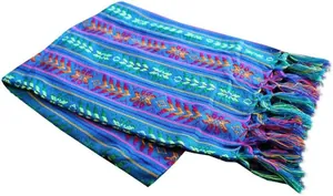 Détail macro d'un chemin de table mexicain bleu avec rayures colorées et franges nouées.
