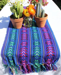 Chemin de table mexicain coloré avec motifs tissés et pompons vibrants dans un jardin