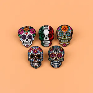 Set of five colorful Mexican sugar skull enamel pins on a plain orange background