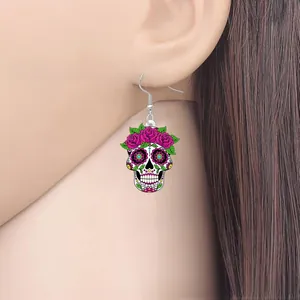 Close-up of a colorful acrylic sugar skull earring with pink roses shown on a model's ear