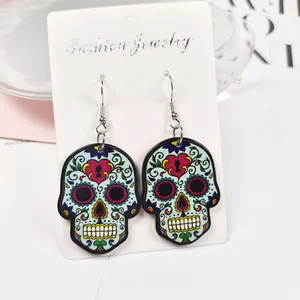 Détail de boucles d'oreilles tête de mort colorées avec des motifs floraux et de cœur.