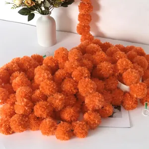 Close-up of bright orange artificial marigold flower garlands for festive decor