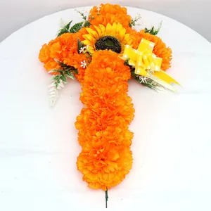 Detail eines orangefarbenen Tagetes-Kreuzes mit Sonnenblume und gelber Schleife.