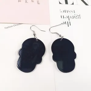 Détail de boucles d'oreilles pendantes en forme de tête de mort noire de style punk