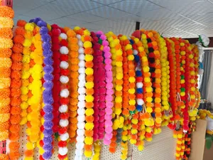 Vibrant artificial marigold flower garlands hanging on a display rack for Indian weddings