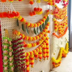 Detail of orange and yellow marigold garlands with gold bells for Indian wedding decor.
