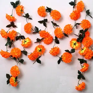 Detailed view of vibrant orange artificial marigold garlands featuring lifelike green leaves.