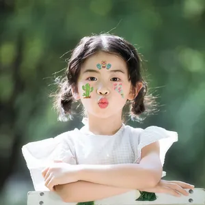 Child model wearing Mexican Day of the Dead face tattoos with cactus and skull designs