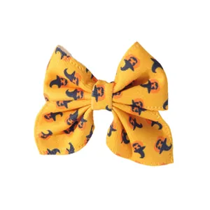 Close-up detail of yellow Halloween bow hair clip featuring pumpkin and witch hat print.
