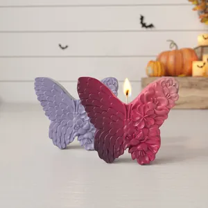 Vista dettagliata di candela a forma di farfalla con motivi floreali in ambiente Halloween.