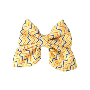Detail view of a colorful bow hair clip with a yellow and orange chevron pattern for children.