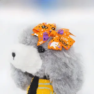 Close-up of orange Halloween pet bow with spooky ghost prints on a gray poodle toy