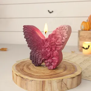 Primo piano di una candela a farfalla con intagli floreali su una base di legno rurale.