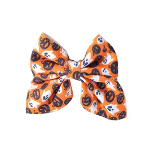 Macro view of Halloween hair bow featuring white ghosts and black pumpkins on orange fabric.