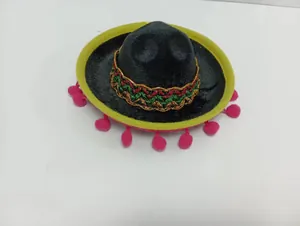 Top view of a mini Mexican sombrero with festive pom-poms on a white surface