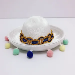 Detail view of a mini white Mexican sombrero hat with colorful pom-poms and gold trim
