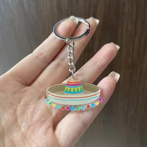 Close-up of a colorful acrylic Mexican sombrero hat keychain held against a wooden background