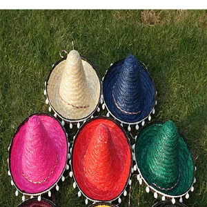 Detailed view of colorful Mexican sombrero straw hats with white pom-pom trim on grass.