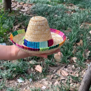Mini Mexican straw hat with colorful ethnic stripes being held in hand for scale