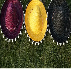Set of three colorful Mexican straw hats with pompom trim displayed on green lawn