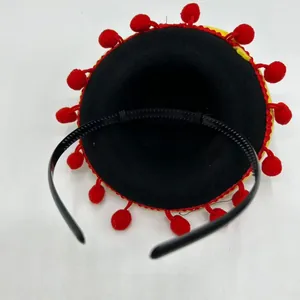 Detail of pet Mexican hat headband with black base and red pom-poms decoration.
